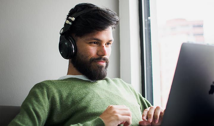 Flexible Universal Life Insurance - Man wearing headphones while working on computer | Photo by Miguelangel Miquelena on Unsplash